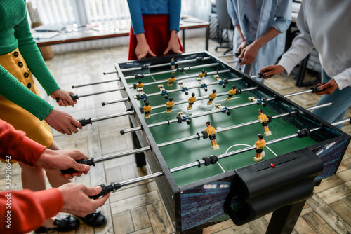 Spending great time together. Cropped photo of young people playing table soccer in the office. Having fun after work photo