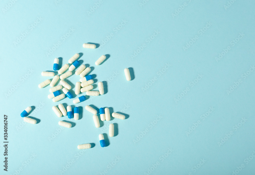 Randomly scattered pills. White and blue pills on blue background. Place for text. Randomly scattered pills. White and blue pills on blue background. Place for text.