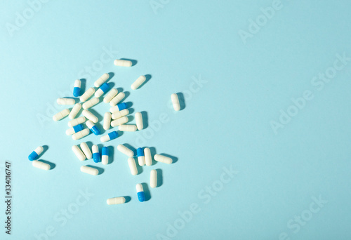Randomly scattered pills. White and blue pills on blue background. Place for text.