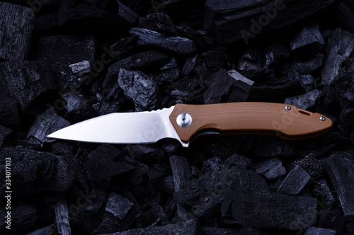 Pocket folding knife with a brown handle. Shiny knife on the corner. Color and contrast. photo