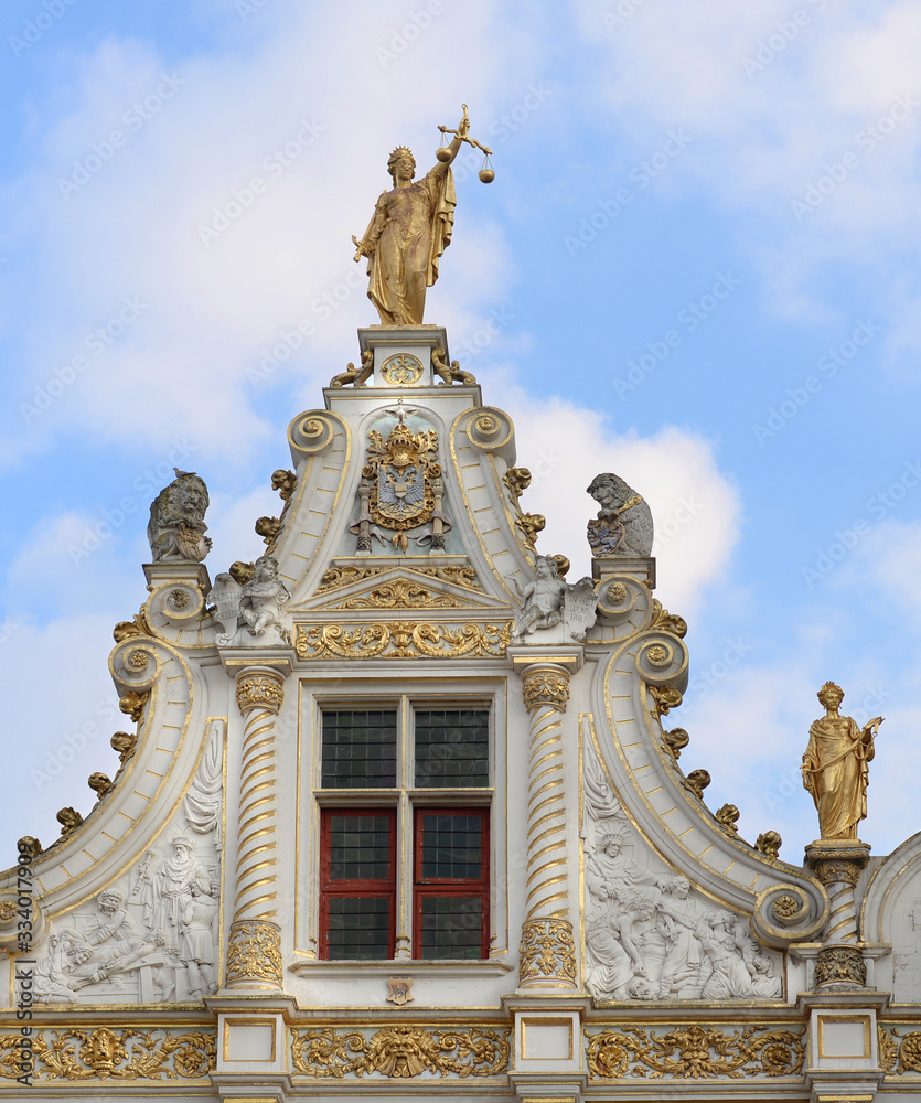 Obraz premium Part of the gable of the Old Civil Registry in Bruges, one of the oldest renaissance buildings in Flanders, with bronze statue of Lady Justice on top