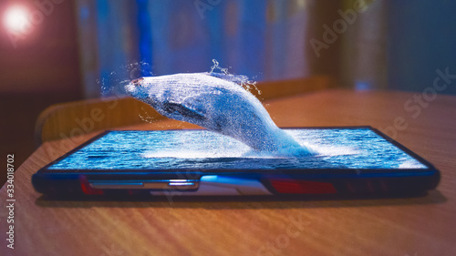 Fotografi Photo manipulation of a whale jumping through the screen of mobile phone