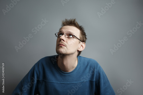 Guy with glasses looks thoughtfully at the side