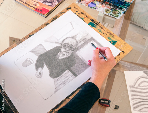 artist drawing a pencil illustration for the second edition of his illustrated children's book, which is on the glass table. Creative environment photo