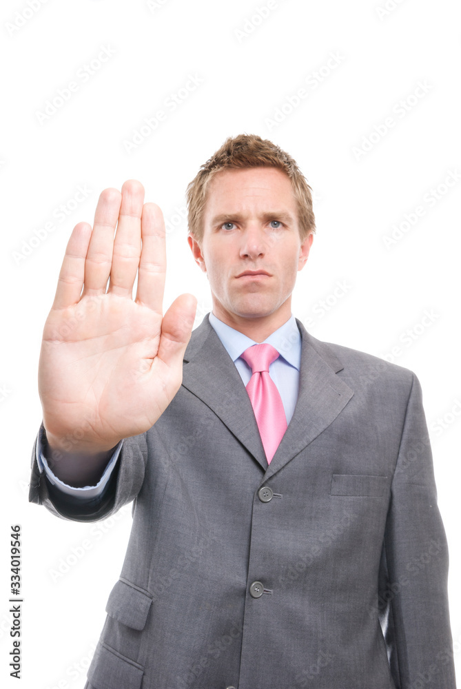 Frowning businessman holding out a warning gesture hand to keep away for social distancing against a white background Frowning businessman holding out a warning gesture hand to keep away for social distancing against a white background