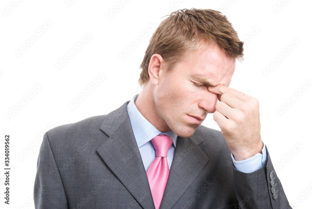Stressed businessman pinching the bridge of his nose to alleviate his headache white background Stressed businessman pinching the bridge of his nose to alleviate his headache white background