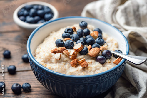 Oatmeal porridge with blueberries and almonds. Healthy breakfast porridge oats on a wooden table. Closeup view. Clean eating food photo