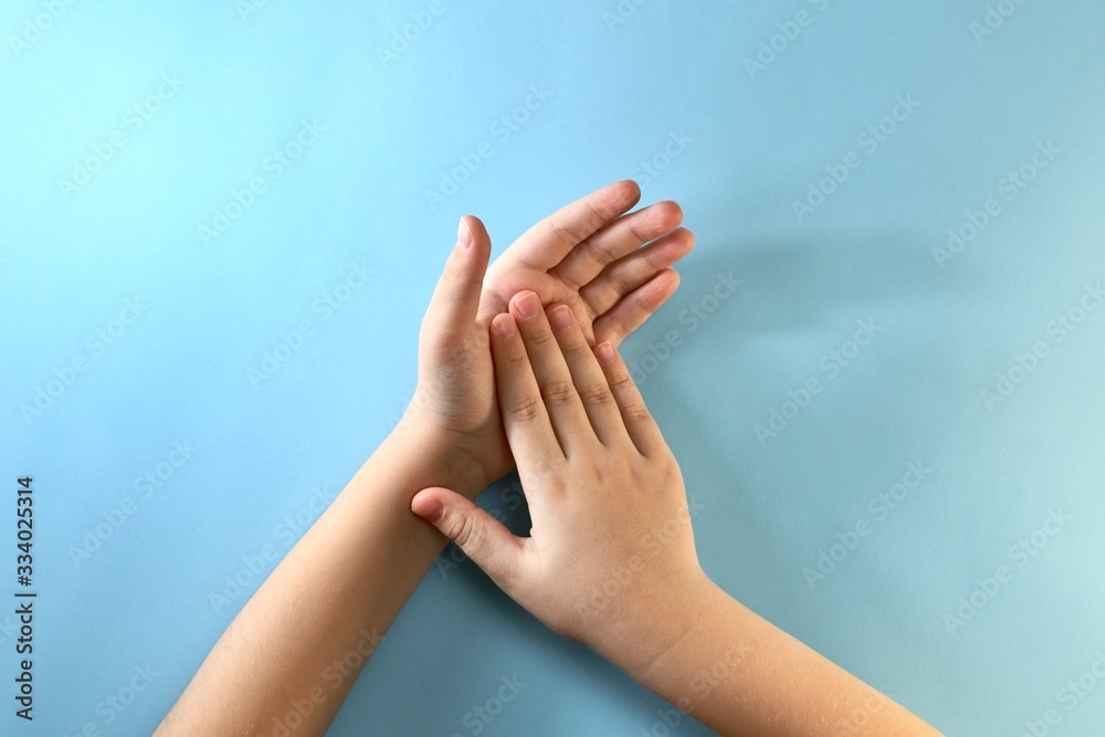 Two children's palms on top of each other on a light blue background. Two children's palms on top of each other on a light blue background.