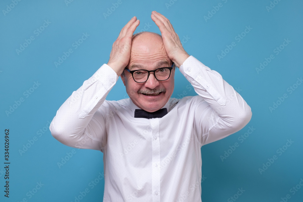 Stressful senior male screams in panic, keeps hands on head Stressful senior male screams in panic, keeps hands on head