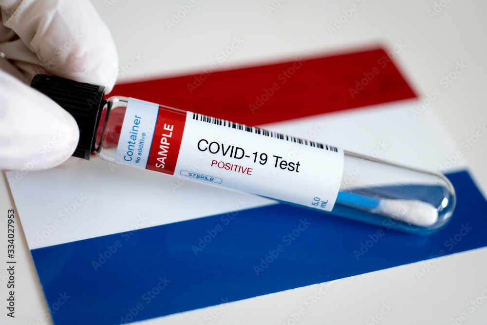 Obraz premium Testing for presence of coronavirus in Netherlands. Tube containing a swab sample that has tested positive for COVID-19. Dutch flag in the background.