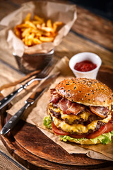 Juicy burger on the board, black background. Dark background, fast food. Traditional american food. Copy space.