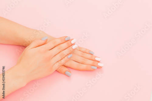 Stylish trendy female manicure. Beautiful young woman's hands on pink background.