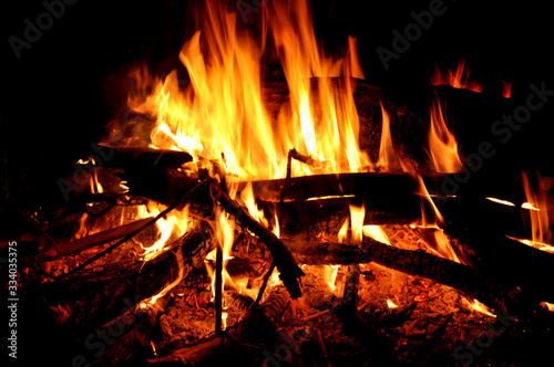 Bonfire close-up near a tourist tent, burning firewood. Orange flame of fire cooking at the stake. Arson or natural disaster.