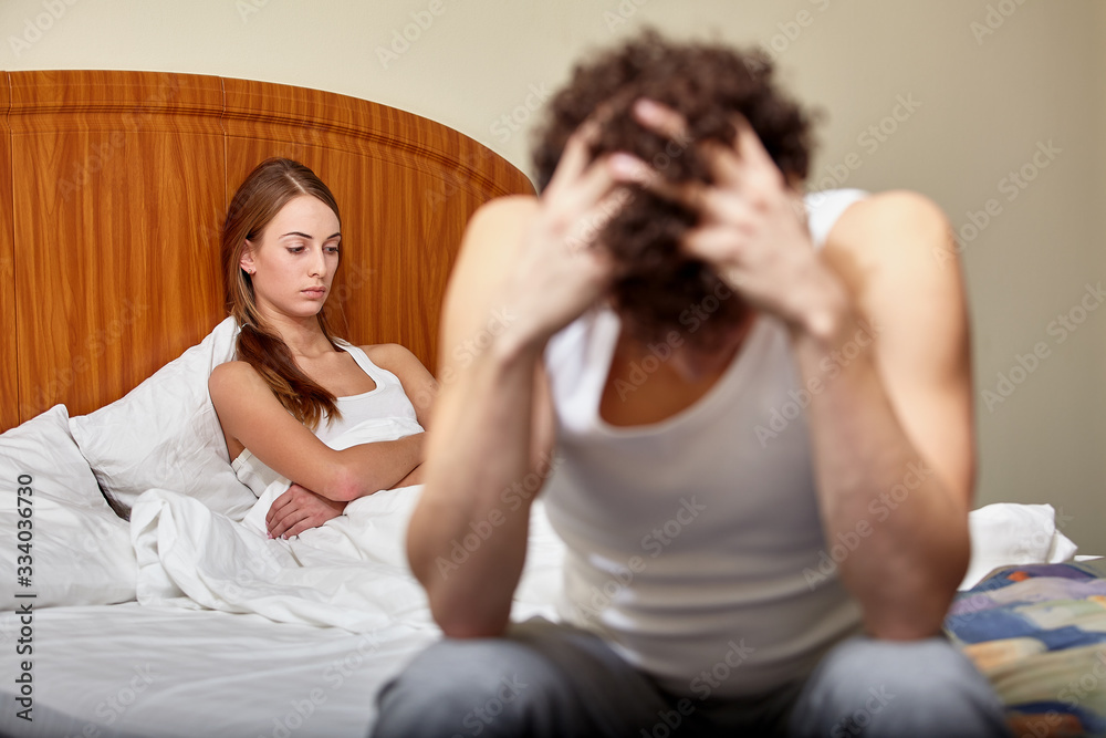 Family conflict. Young couple quarrels in bedroom at home. Selective focus on woman