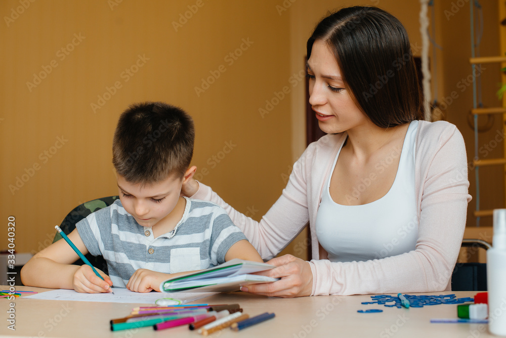 A young mother is doing homework with her son at home. Parents and training A young mother is doing homework with her son at home. Parents and training