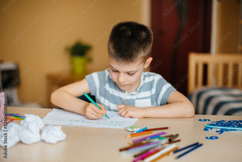 A school-age boy does homework at home. Training at school A school-age boy does homework at home. Training at school