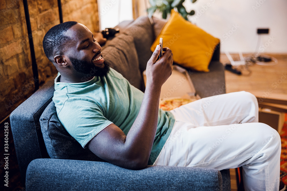 Gladsome man with smartphone on the sofa stock photo