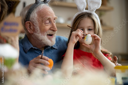 Bilde på lerret Happy elderly man preparing for Easter with granddaughter stock photo