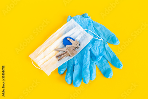 medical mask and gloves lie with keys on a background of yellow color
