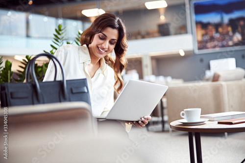 Joyful pretty lady using notebook at business center