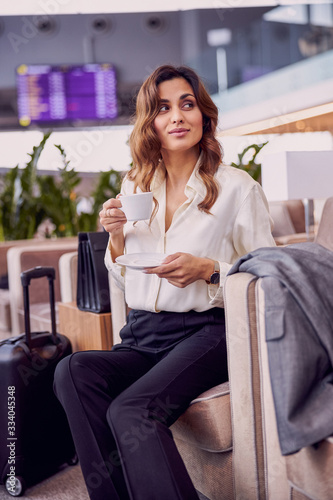 Beautiful lady drinking coffee in airport waiting room