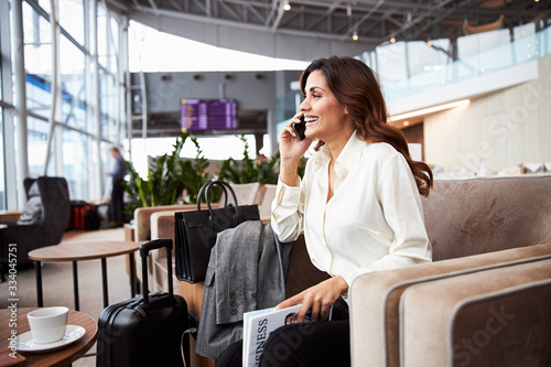 Cheerful lady having phone conversation in departure lounge photo