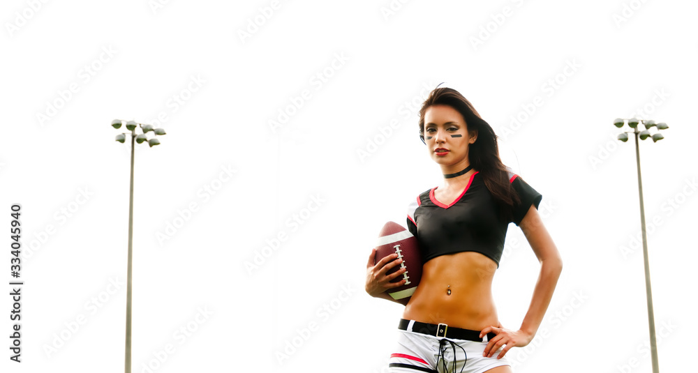 Beautiful woman wearing American Football top and shorts holding ball on field. Beautiful woman wearing American Football top and shorts holding ball on field.