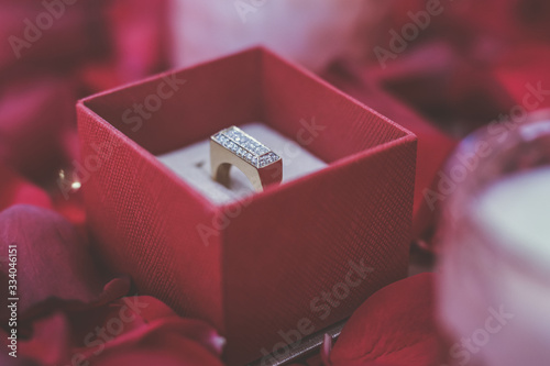 Beautiful wedding rings in red rose petals with candles close up
