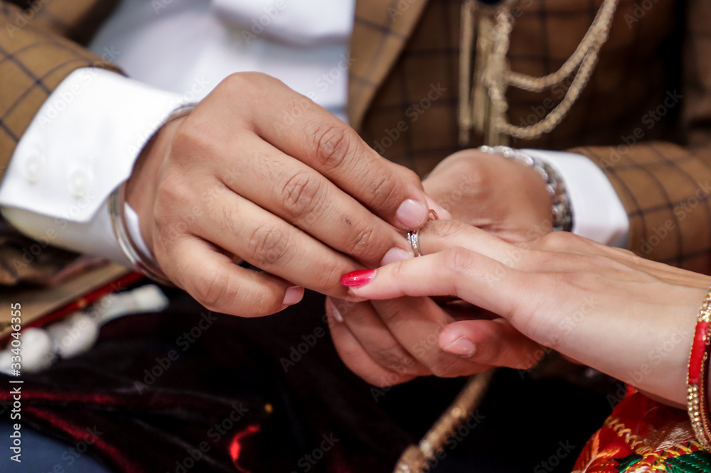 Engaged couple is exchanging wedding rings hands close up