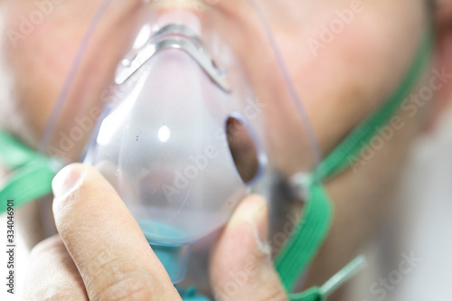 The bearded man has an oxygen mask on his face. Close-up. The patient has trouble breathing. Close up.