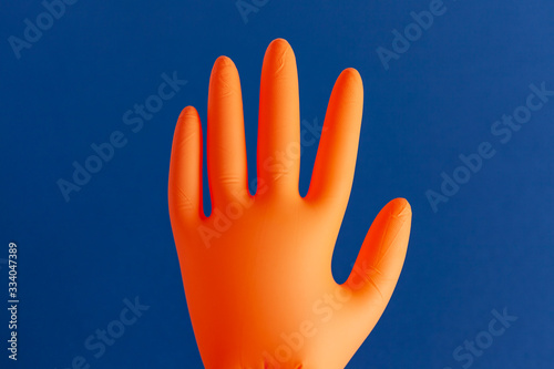 Inflated orange rubber glove isolated on blue background