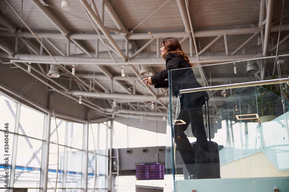 Stylish lady standing on second floor of airport waiting zone Stylish lady standing on second floor of airport waiting zone