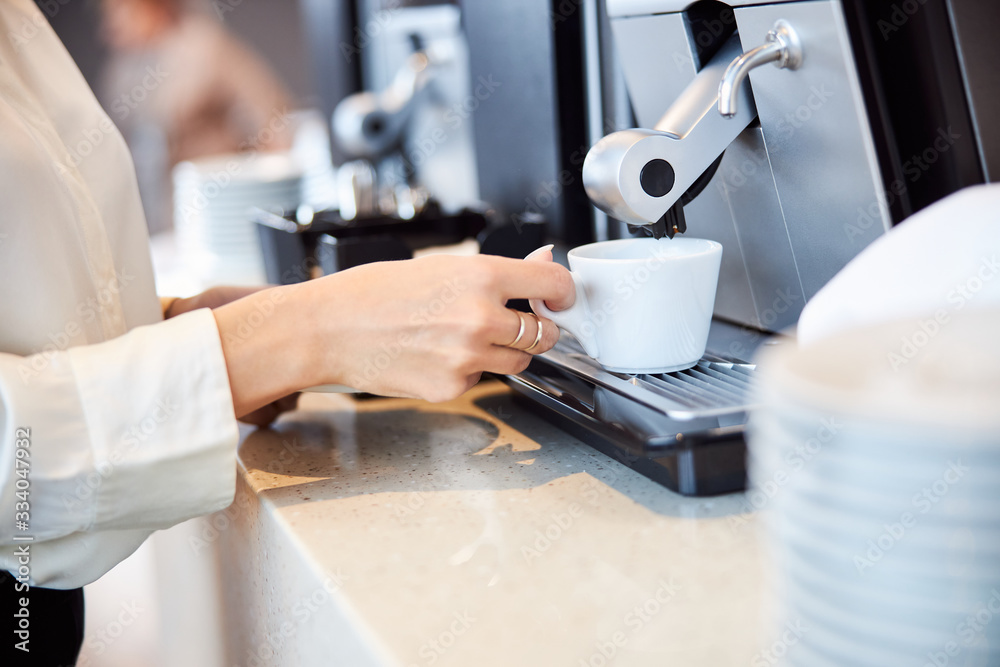 Young woman making fresh espresso with automatic coffee machine