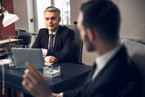 Bearded man in suit having chat with office worker indoors