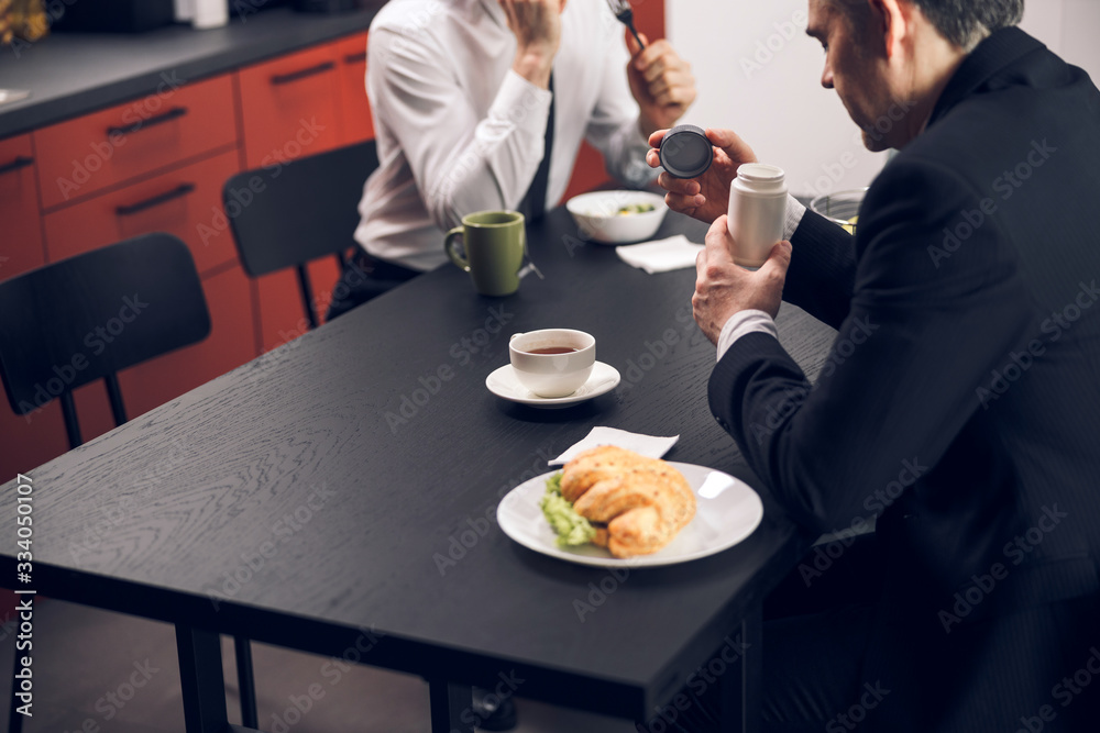 Caucasian young men drinking tasty beverage during lunchtime