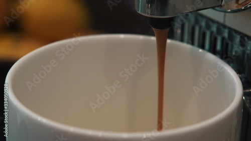 Close up of a coffee machine dispensing fresh hot coffee into a white cup