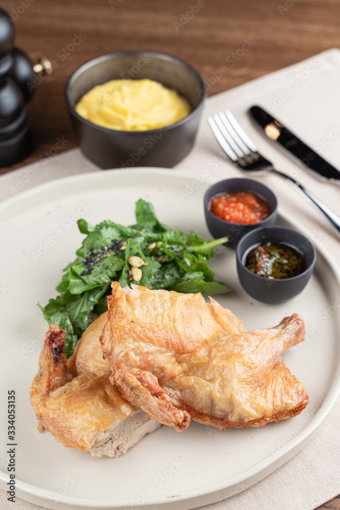 Whole chicken baked and sliced in halves with herbs and sauces in a restaurant