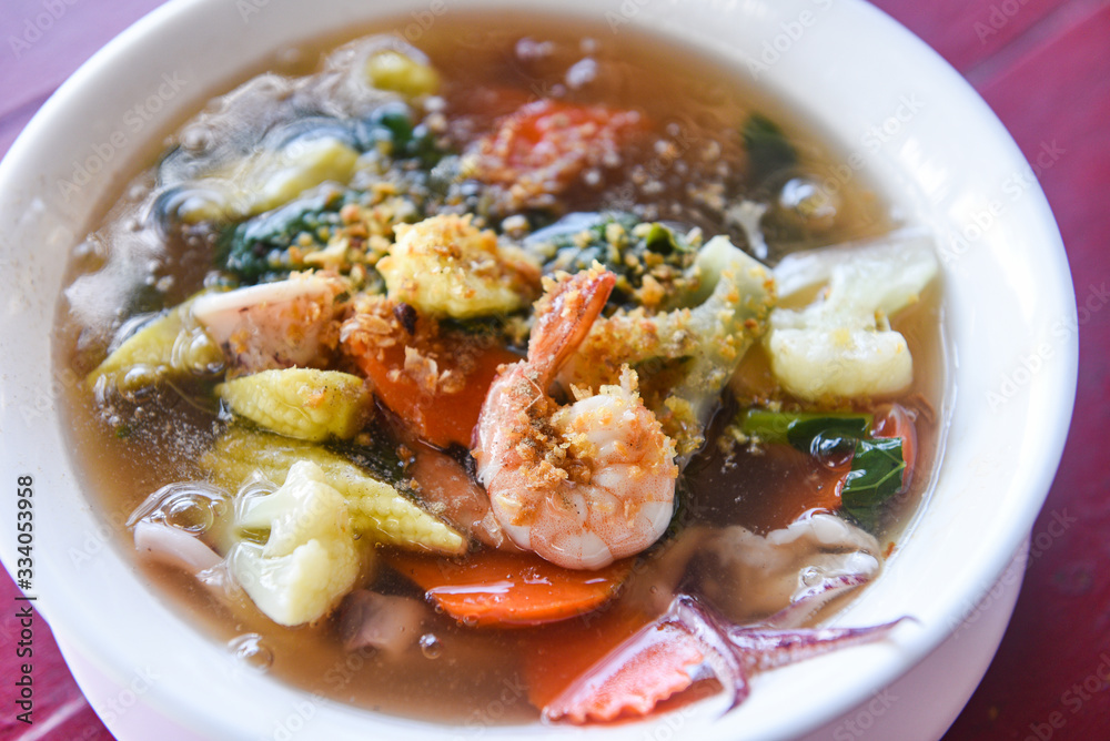 Thick Gravy seafood noodles with squid shrimp prawn and vegetable on bowl on wooden table background - Thick Gravy seafood noodles with squid shrimp prawn and vegetable on bowl on wooden table background -