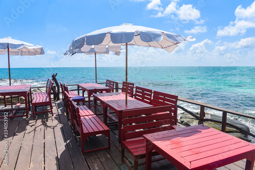 Terrace view sea with wooden table and chairs on the beach landscape nature with sunlight on umbrella - wooden balcony view seascape idyllic seashore restaurant by sea in the resort © Bigc Studio