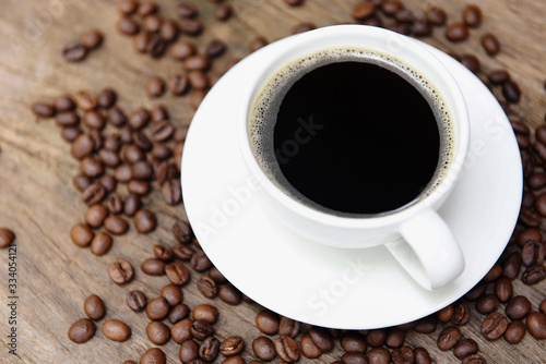 Coffee cup and coffee beans on table / black coffee in white mug on wooden background