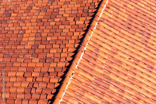 Elevated view of classic red tile clay roof with ridge tile. One cracked tile is visible.