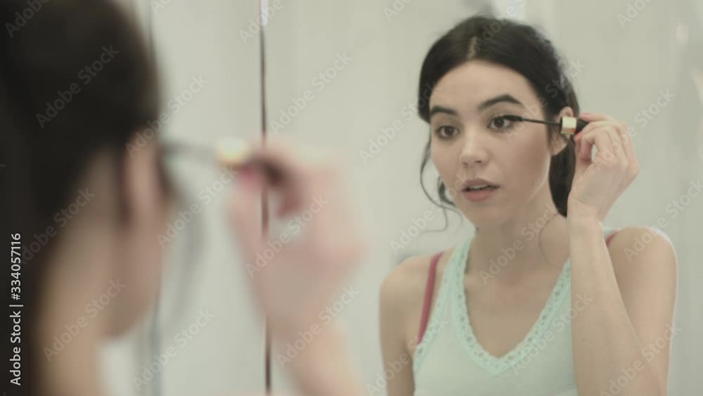 Pretty Young Asian female applying make up in bathroom Pretty Young Asian female applying make up in bathroom