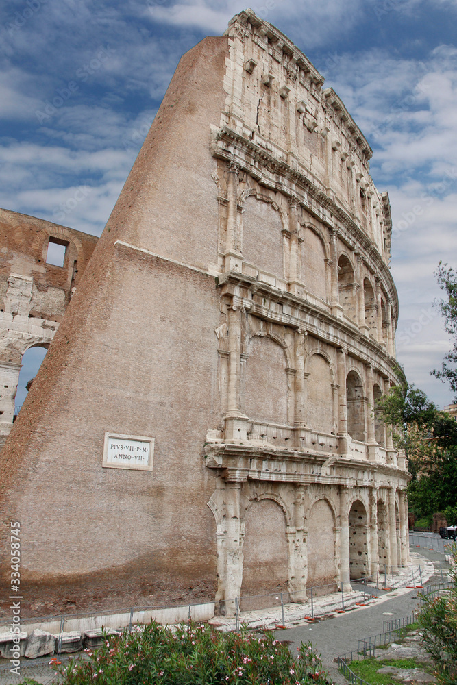 The exterior facade of the Colosseum or Coliseum with the arches against blue sky in Rome, Italy