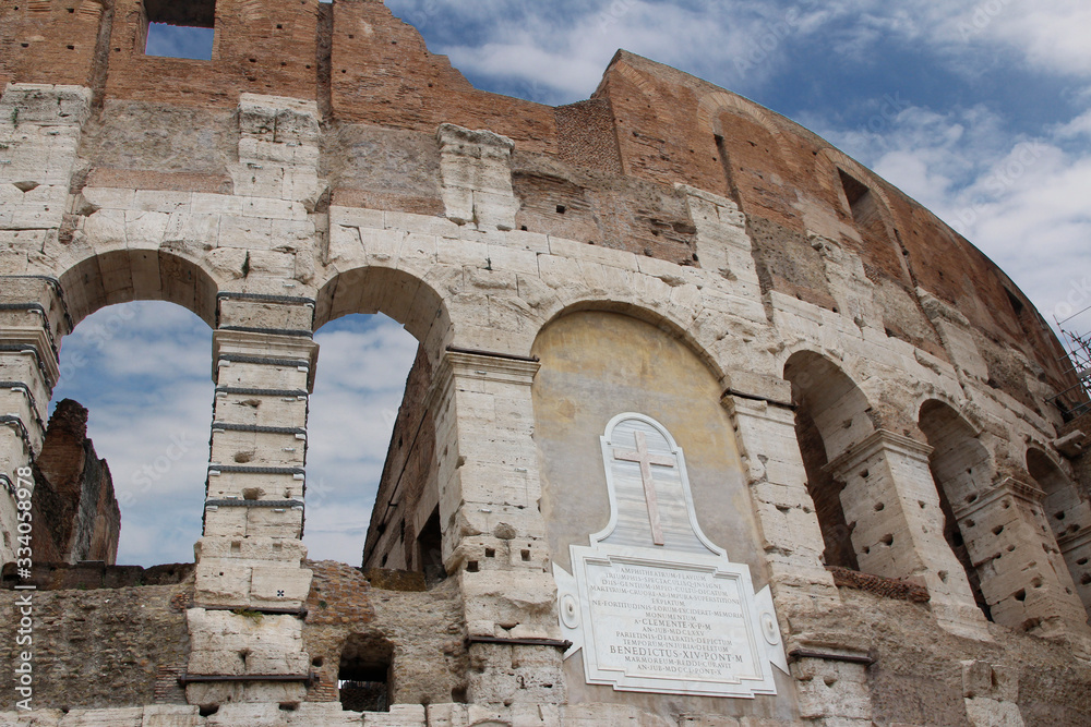 The exterior facade of the Colosseum or Coliseum with the arches against blue sky in Rome, Italy