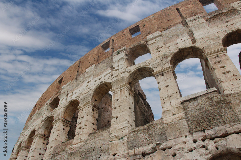 The exterior facade of the Colosseum or Coliseum with the arches against blue sky in Rome, Italy