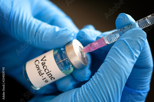 Photos doctor's hand holds a syringe and a blue vaccine bottle at the hospital