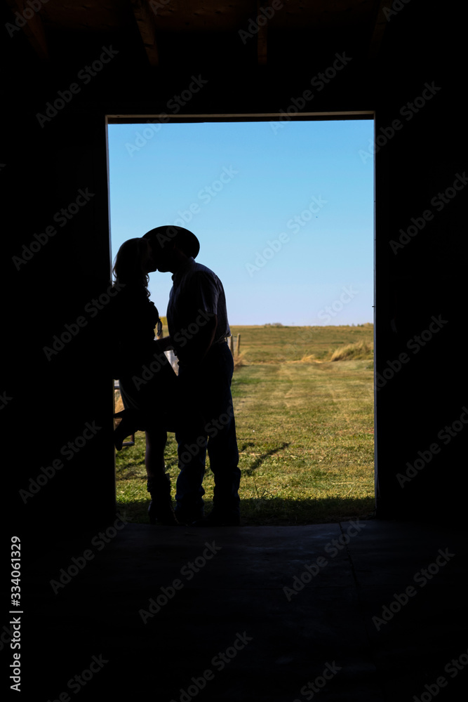 Silhouette of cowboy and cowgirl kissing 