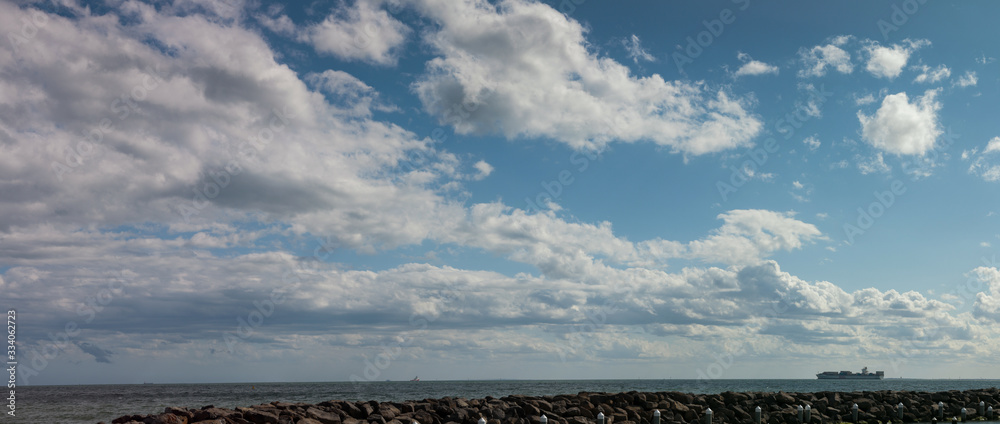 Fototapeta premium panorama of a large container ship leaving Melbourne harbour bay entering international shipping waters on a sunny blue sky day off the south coast of Melbourne, Victoria, Australia