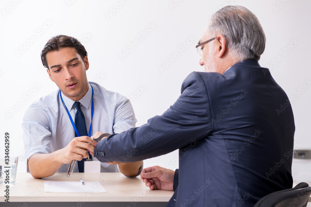 Old businessman meeting with advocate in pre-trial detention Old businessman meeting with advocate in pre-trial detention