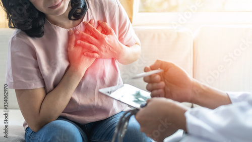 Chest pain illness causing heart attck and stroke risk in woman patient with doctor examing and diagnosing patient health in hospital clinic photo
